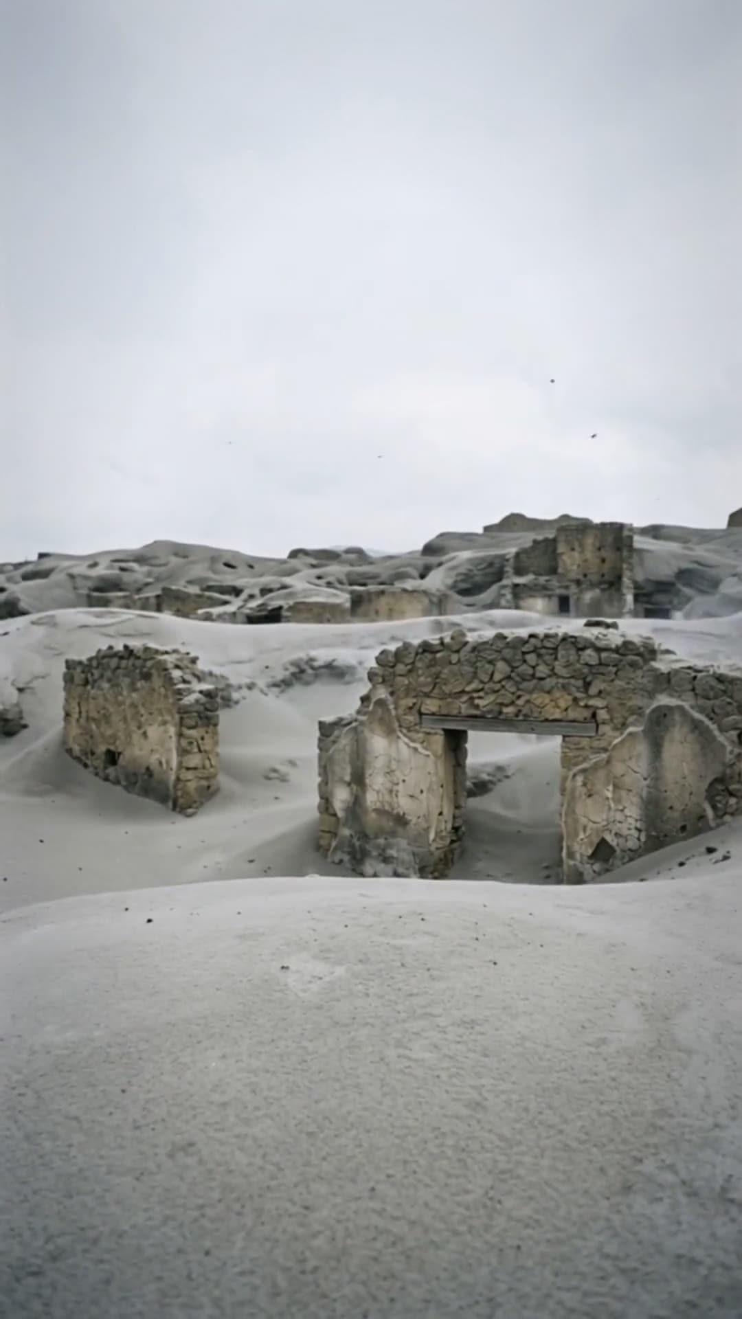 A vertical view of Pompeii ruins buried under pale volcanic ash.